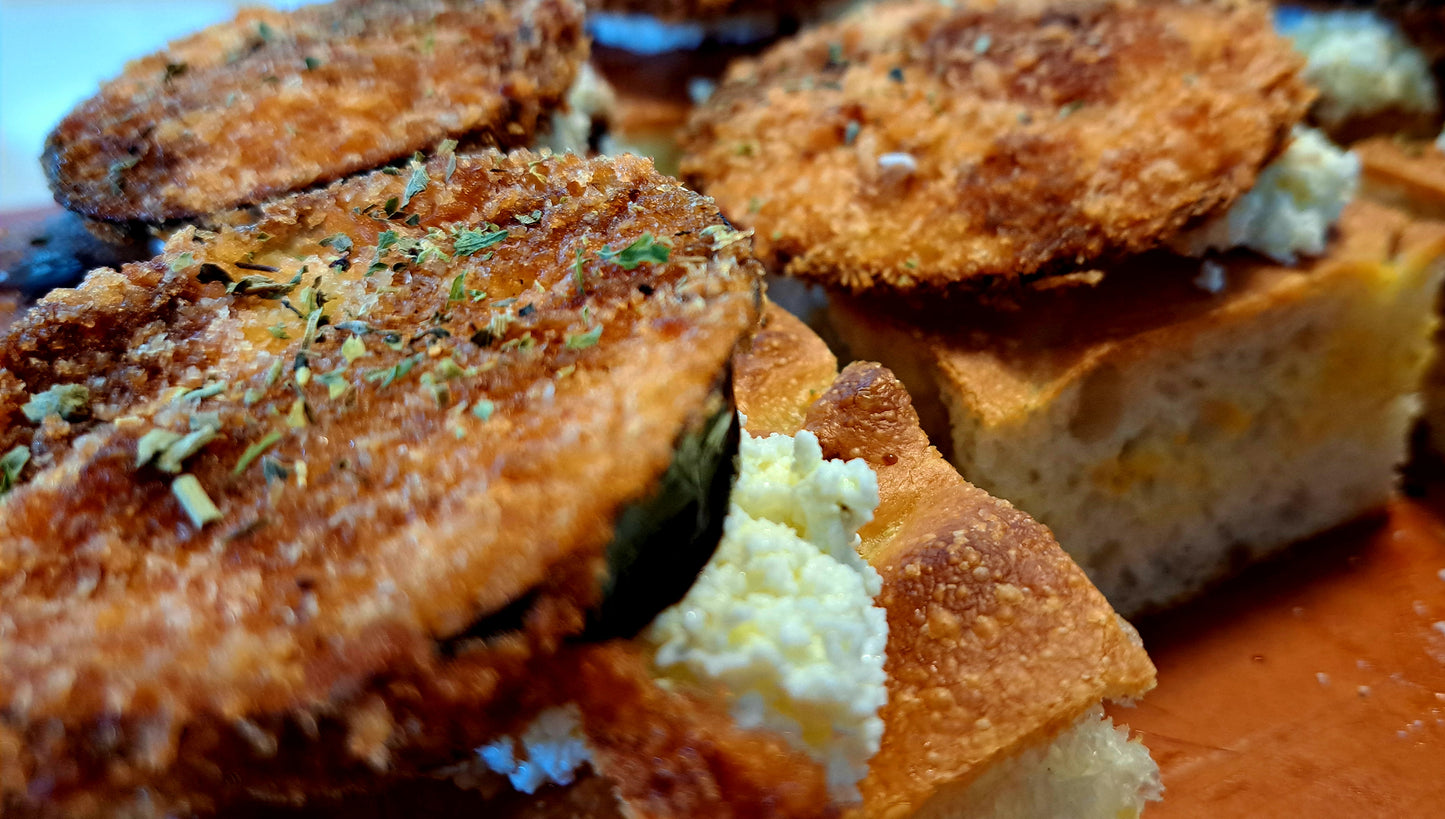 Focaccia with cream cheese, spread on top and topped with a deep fried eggplants. Garnished with dried herbs and balsamic reduction.