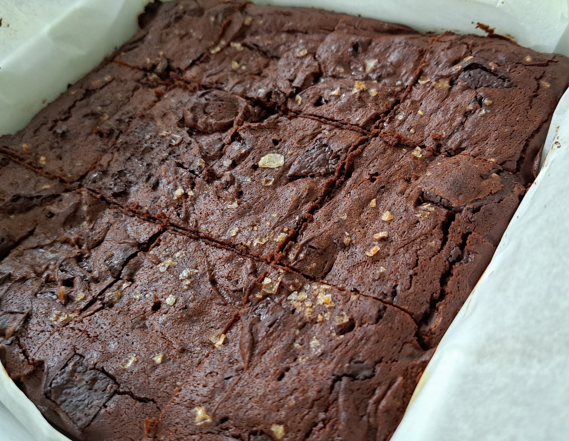 Tray baked brownies. Topped with sea salt and dark chocolate chips. Fudgy interoir with a crispy exterior.