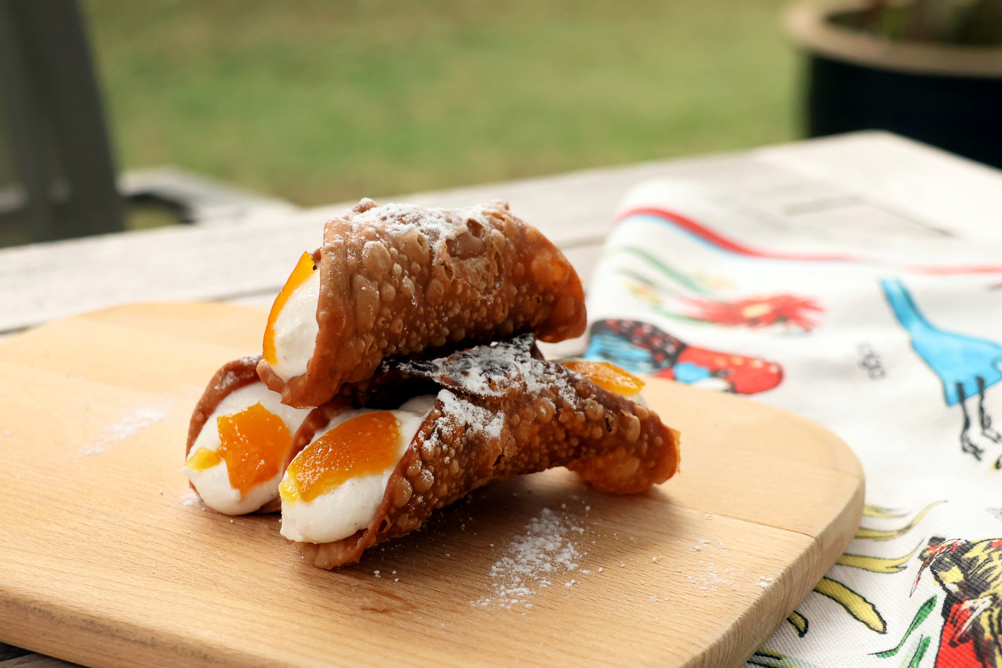 Deep fried cannoli, filled with ricotta cream and the ends topped with a sliced of marianted orange peels. Typically described as arancia in terms of flavror.