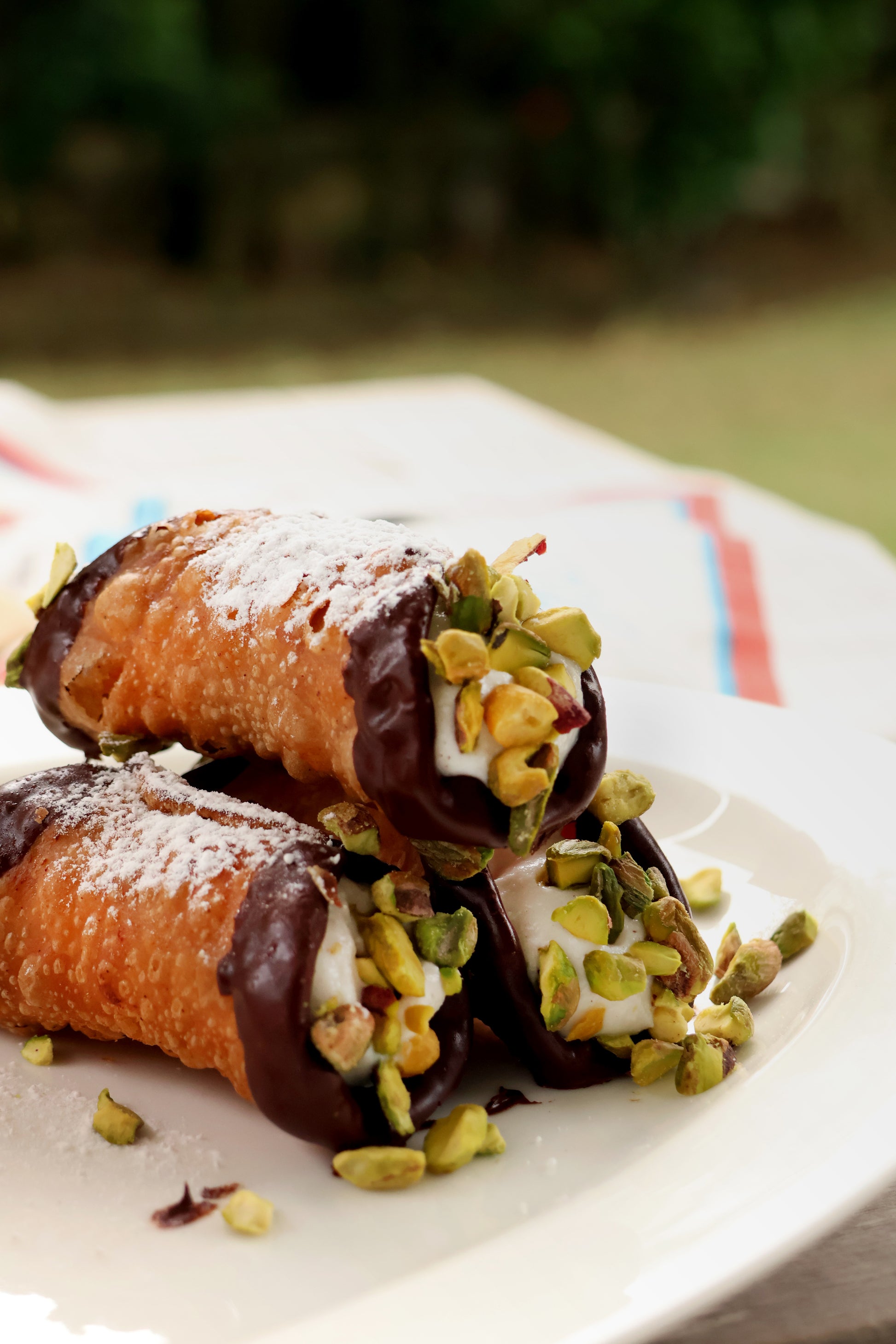 Deep fried crispy cannoli, filled with ricotta cream. Ends are coated in dark chocolate and top with pistachios