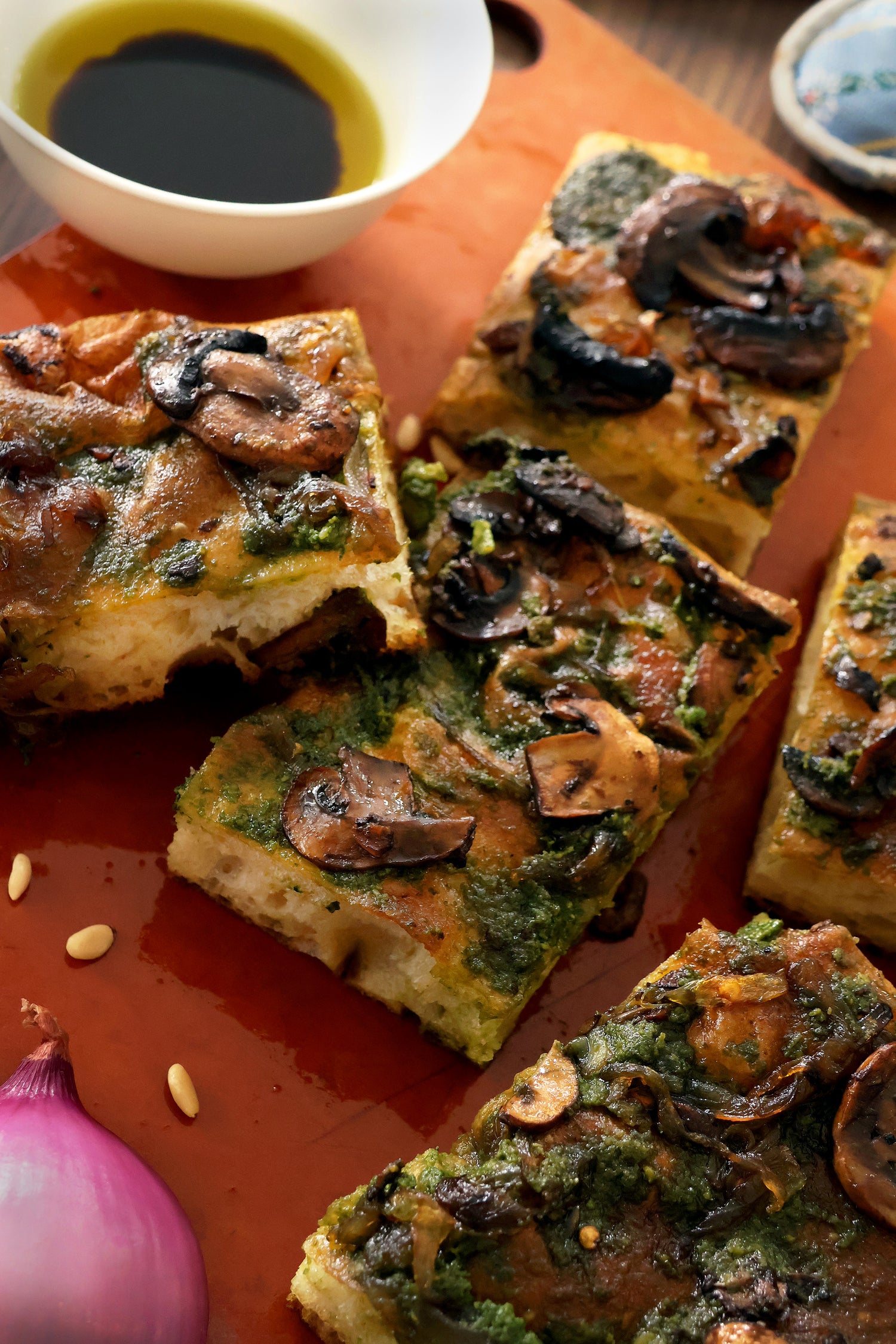 A focaccia made from 00 flour and semolina flour. Golden and cripsy exterior. Topped with basil pesto, caramilesed onions and mushrooms marianeted in balsimic vinegar