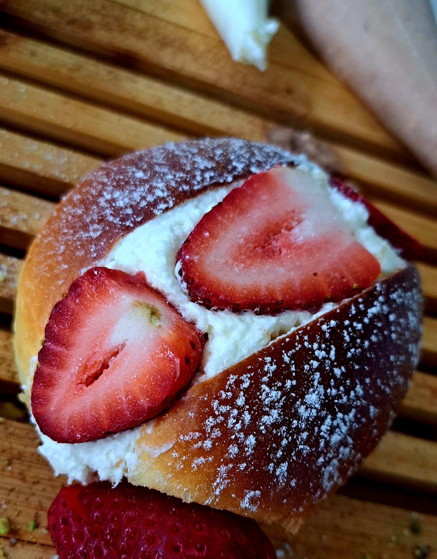 Single maritozzo, a traditional Italian sweet bun, presented in a close-up view. Berry flavour, topped with strawberries and filled with jam.